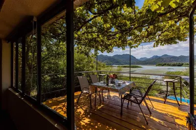 a table and chairs on a deck with a view of a river at Lake House Buric in Vranjina