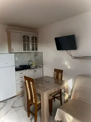 a kitchen with a wooden table and chairs and a refrigerator at Apartmani Orlović Bar in Bar