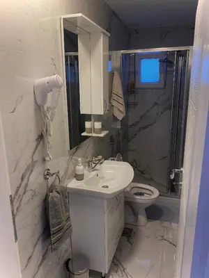 a white bathroom with a sink and a toilet at Apartmani Orlović Bar in Bar