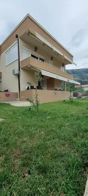 a house with a grass field in front of it at Deluxe Apartmani Vila Pejovic Sutomore in Sutomore