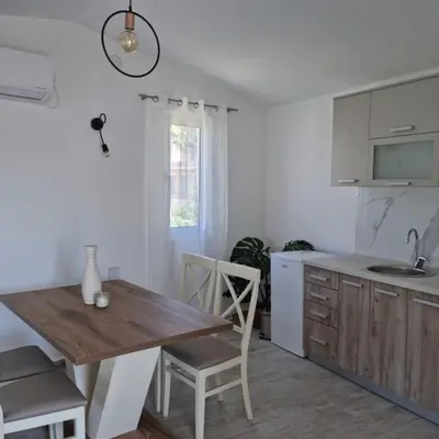 a kitchen with a wooden table and a dining room at The Apartment in Ulcinj