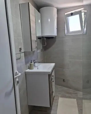 a bathroom with a white sink and a window at The Apartment in Ulcinj