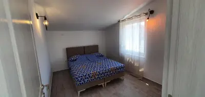 a bedroom with a bed with a blue comforter and a window at The Apartment in Ulcinj