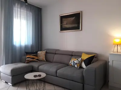 a living room with a gray couch with pillows at Budva center apartmant in Budva