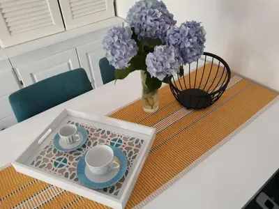 a table with two cups and a vase of purple flowers at Budva center apartmant in Budva