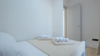 a white bedroom with two towels on a bed at Silver Beachfront Becici in Becici