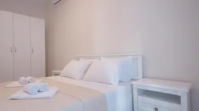 a white bedroom with a bed with towels on it at Silver Beachfront Becici in Becici