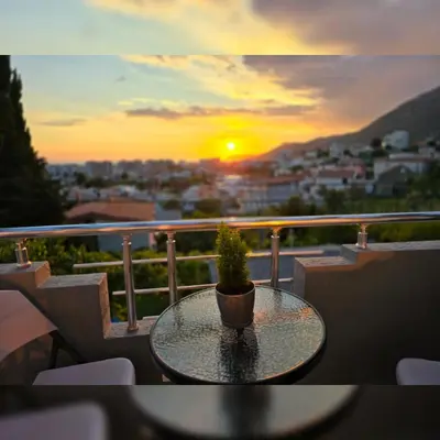 a table with a plant on a balcony with the sunset at Family apartment-DiLorena in Bar