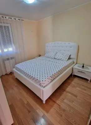 a white bed in a bedroom with a wooden floor at Family apartment-DiLorena in Bar