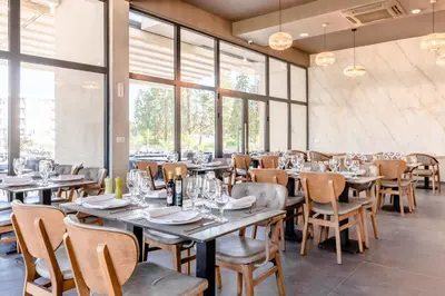 a dining room with tables and chairs and windows at Hotel Olea in Ulcinj