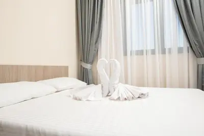 a white bed with white sheets and white shoes on it at IPN ROOMs in Mahala
