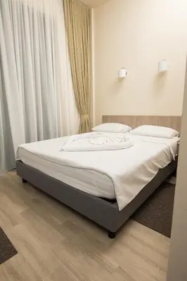 a bedroom with a bed with white sheets and curtains at IPN ROOMs in Mahala