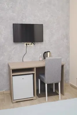 a desk with a chair and a television on a wall at IPN ROOMs in Mahala