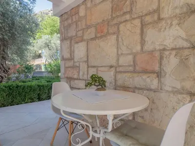 a white table and chairs in front of a stone wall at Tomy Garden House in Budva