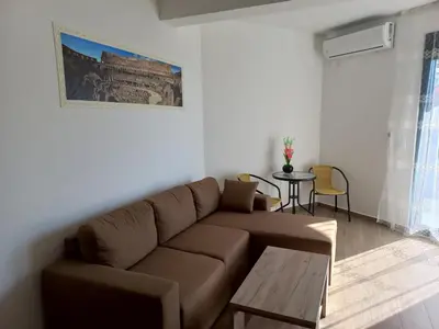 a living room with a brown couch and a table at Sea View Dobra Voda in Dobra Voda