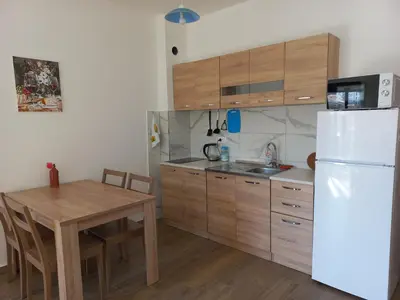 a kitchen with a table and a white refrigerator at Sea View Dobra Voda in Dobra Voda