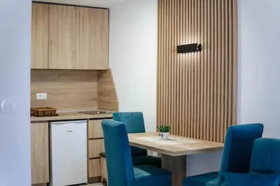 a kitchen with a wooden table and blue chairs at OLIVE GARDEN APARTMENT in Bar
