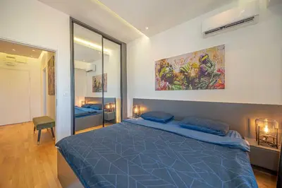 a bedroom with a blue bed and a painting on the wall at Night Pearl - Deluxe Apartment in Bar