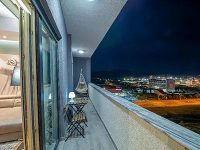 a balcony with a view of a city at night at Night Pearl - Deluxe Apartment in Bar
