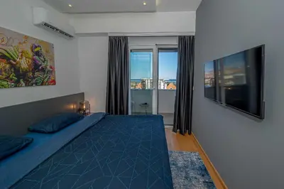 a bedroom with a blue bed and a large window at Night Pearl - Deluxe Apartment in Bar
