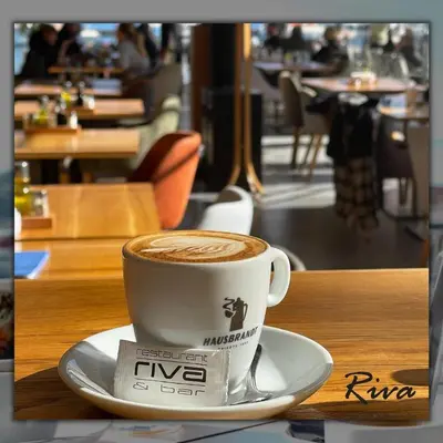 a cup of coffee sitting on a plate on a table at Hotel Riva in Budva