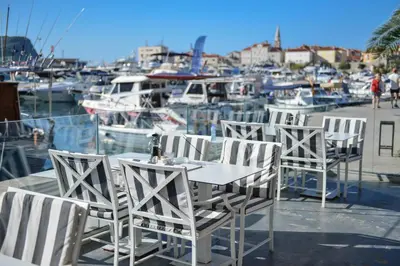 a table and chairs sitting on a dock with boats at Hotel Riva in Budva