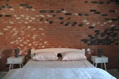 a bedroom with a brick wall and a bed with pillows at Una Apartment Cetinje in Cetinje