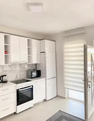 a white kitchen with white cabinets and a microwave at Sam Villa in Ulcinj