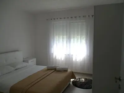 a white bedroom with a bed and a window at Sam Villa in Ulcinj