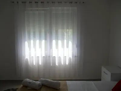 a bedroom with a window with white curtains and two towels at Sam Villa in Ulcinj