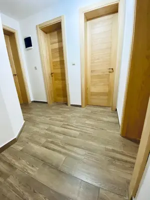 a hallway with three doors and a wooden floor at Talia Apartments in Budva