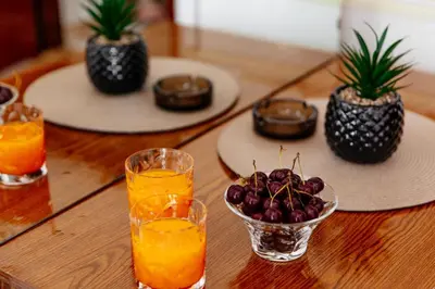 a wooden table with glasses of orange juice and a bowl of fruit at Castello Apartments in Ulcinj