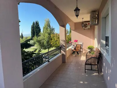 a balcony with chairs and a view of a garden at Large Three-Bedroom Apartment 2 Min from Airport in Podgorica