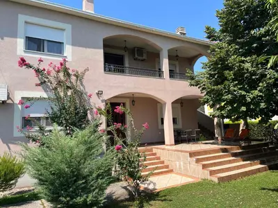 a house with stairs and flowers in front of it at Large Three-Bedroom Apartment 2 Min from Airport in Podgorica