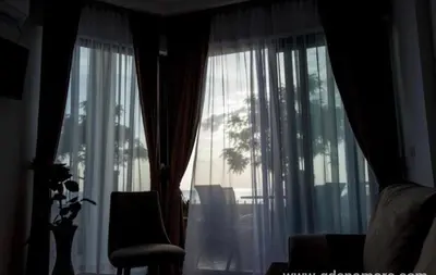a room with a window with curtains and a chair at DeLux Apartmani in Dobra Voda