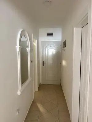 a hallway with a white door and a tile floor at Apartman Na pjenu od mora Becici in Budva