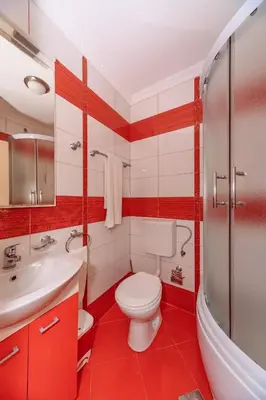 a red and white bathroom with a toilet and a sink at Ani Lux in Dobra Voda