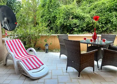 a patio with a table and chairs and a vase with a rose at Jardin de fleurs in Petrovac na Moru