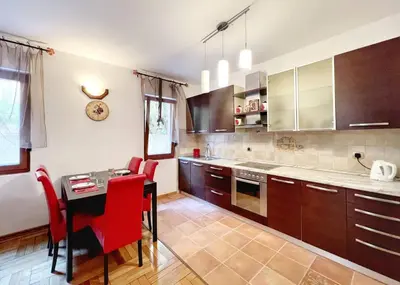 a kitchen with a table and red chairs in it at Jardin de fleurs in Petrovac na Moru
