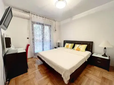 a bedroom with a large bed and a television at Jardin de fleurs in Petrovac na Moru