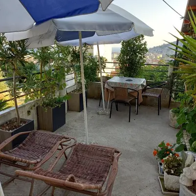 a patio with a table and chairs and an umbrella at Bugenvilija in Budva