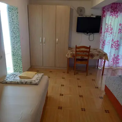 a room with a bed and a table and a tv at Bugenvilija in Budva