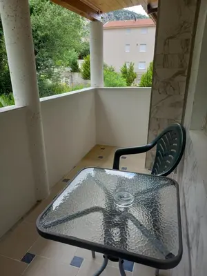 a glass table and a chair on a balcony at Bugenvilija in Budva