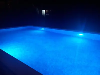an empty swimming pool at night with blue lights at Rustic Village House 4 in Rijeka Crnojevića