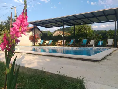 a swimming pool with chairs and a pavilion at Rustic Village House 4 in Rijeka Crnojevića