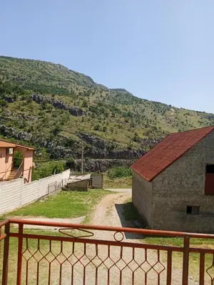 a building with a fence next to a mountain at Villa Natalija in Podgorica