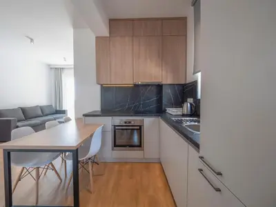 a kitchen with white cabinets and a table and chairs at Horizon one bedroom apartment NS in Becici