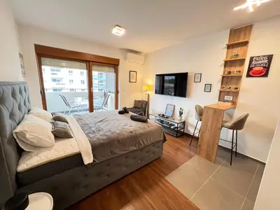 a bedroom with a bed and a desk and a balcony at White Homes 16 - Master Quart in Podgorica