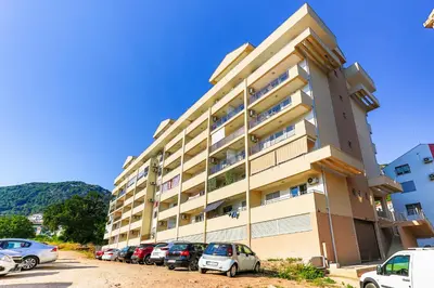 a large building with cars parked in a parking lot at Sonja Apartment in Budva