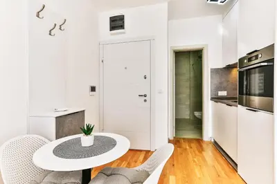a white kitchen with a white table and chairs at Sonja Apartment in Budva